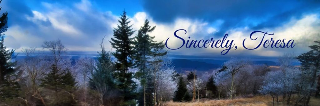 View from mountaintop with mountains in the distance, trees in the forefront, and blue skies, with Sincerely Teresa written on it