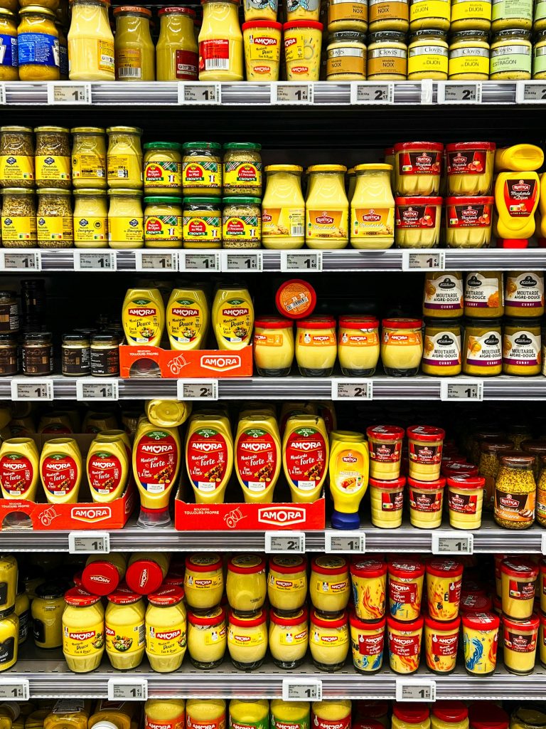 Colorful display of mustard jars on a supermarket shelf in Calais, France, showcasing variety and choice.