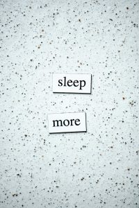 Motivational quote 'sleep more' on a minimalist speckled surface.
